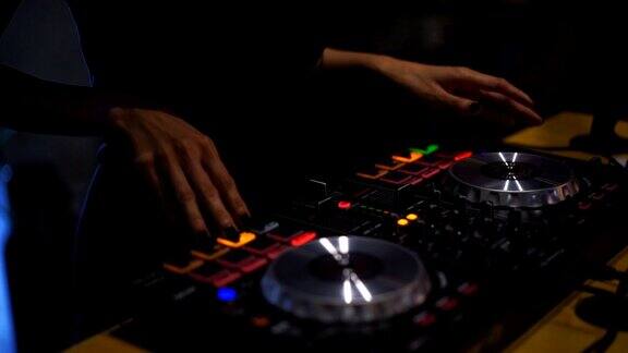 特写镜头双手的DJ甲板转盘混音控制台在迪斯科派对夜总会为庆祝活动