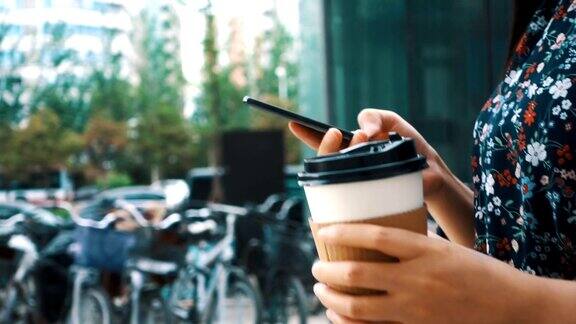 一个拿着咖啡拿着手机走在街上的女孩