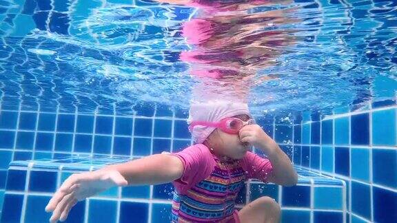 快乐的小女孩在游泳池里潜水家庭暑假