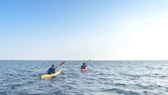 两个人在阳光下划着皮划艇横渡大海