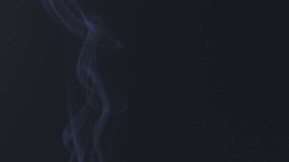 在慢镜头中蓝色烟雾在黑色背景上升起