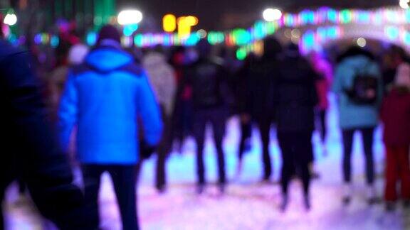 冬季运动概念晚上在城市溜冰场的人群一大群开心的人在滑冰雪下降圣诞天模糊运动和好心情家庭和幸福的夫妇滑冰