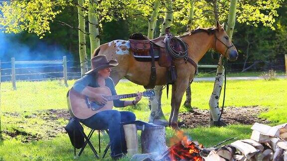 女牛仔在篝火边和马玩吉他