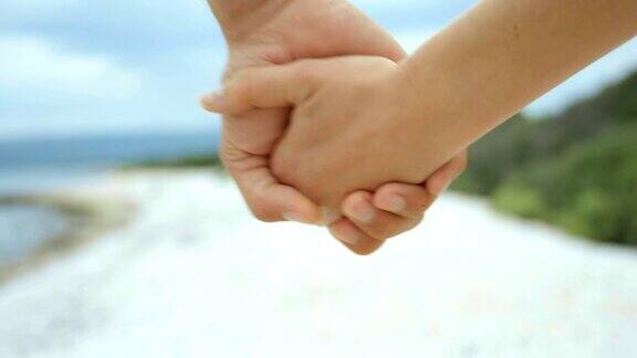 一对夫妇手牵着手在海滩上散步