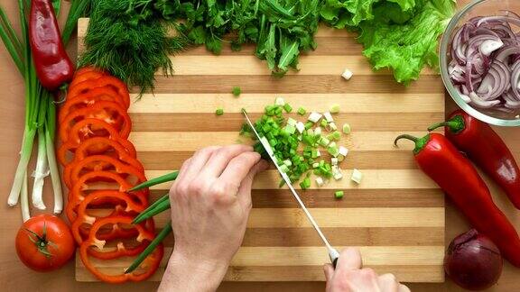男厨师在切菜板上切绿色蔬菜的上图