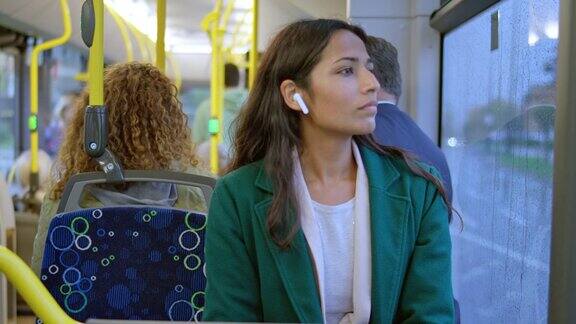 一个女人坐在公交车上把手机拿了出来
