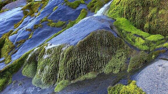水流过光滑平坦的石头形成小瀑布和青苔