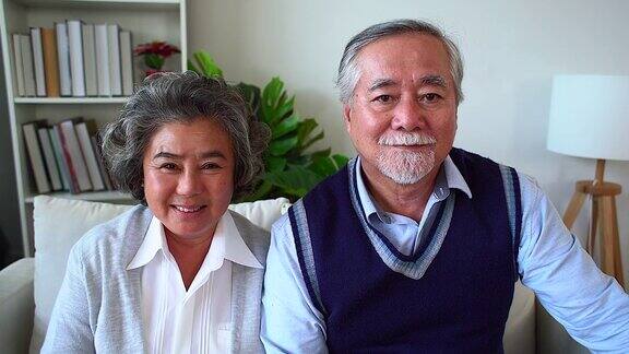 快乐的亚洲老年夫妇享受生活一对浪漫的老年夫妇坐在家里的沙发上大笑