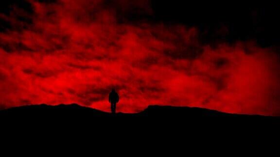 红色天空上的人走过山丘剪影