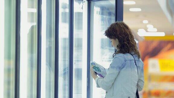 女孩仔细挑选着酷炫的陈列柜里的产品一个年轻女子打开冰箱拿出一袋冷冻蔬菜
