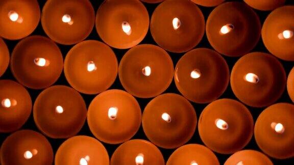 许多燃烧着的圆圆的小蜡烛在黑暗中燃烧火的背景