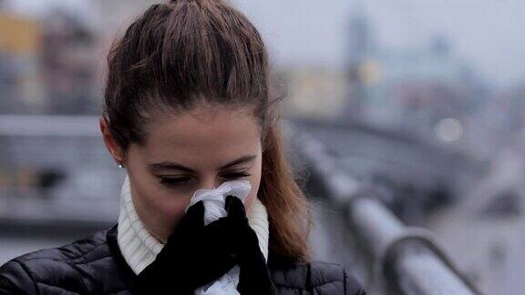 肖像女人打喷嚏和吹鼻子在流感季节城市