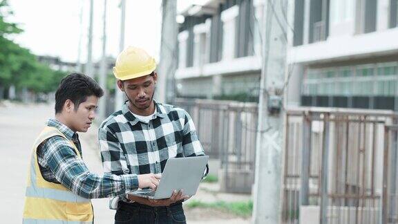 工程师和建筑师戴着安全帽在工地用笔记本电脑讨论住房开发项目承建商经理检查楼宇基础设施