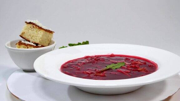 红罗宋汤配肉美味的红色罗宋汤配酸奶油和香草放在白色盘子里传统的乌克兰甜菜根汤红色罗宋汤和大蒜饺子