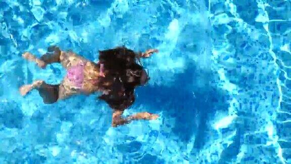 年轻美丽的女孩在粉红色比基尼漂浮在酒店的游泳池在一个阳光明媚的日子里一个不可辨认的棕色头发的女人在清澈的蓝色水池里游泳暑假或假期俯视图特写