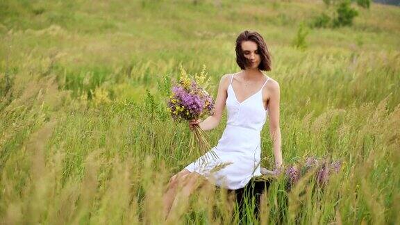 美丽的年轻姑娘在夏天的田野里开着花