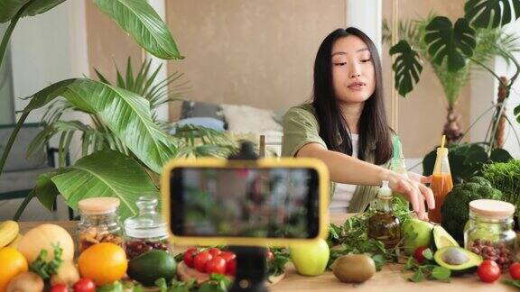 快乐的亚洲女性烹饪视频博主直播她的视频博客的追随者