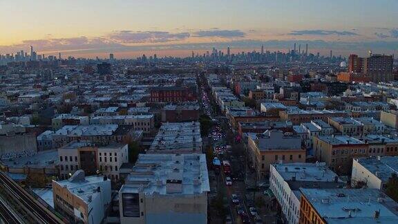 在纽约布鲁克林布什维克住宅区的街道上夕阳西下远处的曼哈顿景色尽收眼底无人机视频与平移摄像机运动