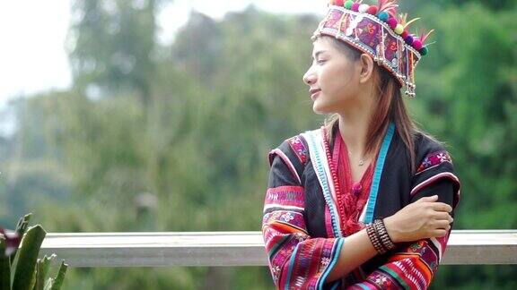 亚洲游客妇女穿着Akha部落和享受在一个木制平台与山的背景