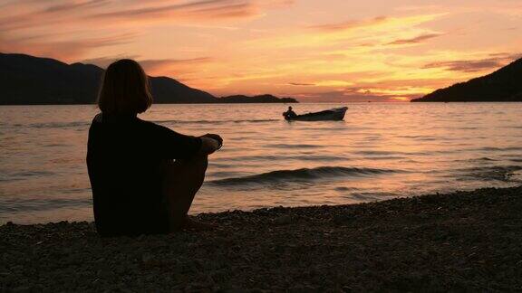 剪影宁静的女人享受宁静的日落海景从海滩慢镜头