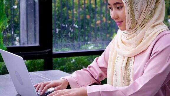 年轻的亚洲穆斯林妇女戴着头巾在办公室使用笔记本电脑和文件