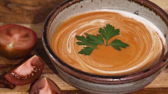 美味的奶油番茄汤与鲜奶油和新鲜的绿色欧芹在碗中关闭
