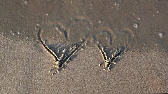 在沙滩上画心形日落时被海浪抹去