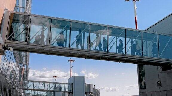 乘客通过玻璃登机桥下飞机