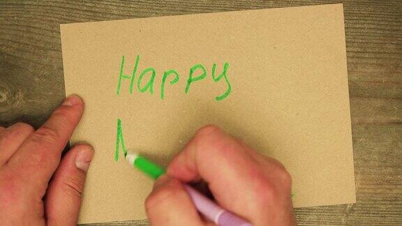 一个男人的手用绿色毡尖笔在纸板上写着新年快乐