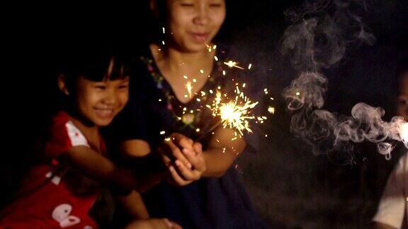 幸福的家庭年轻的妈妈和女孩在晚上拿着火花