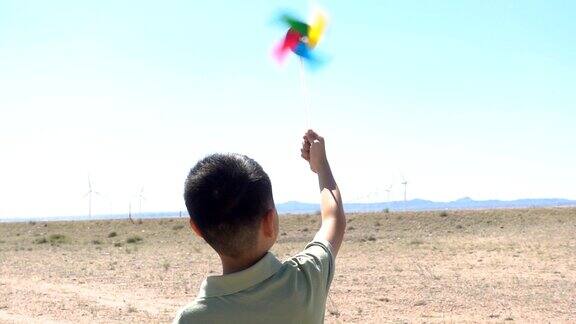 亚洲男孩玩风车朝向风电场