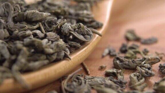 干的绿茶茶叶落入一个木制的乡村勺子慢动作