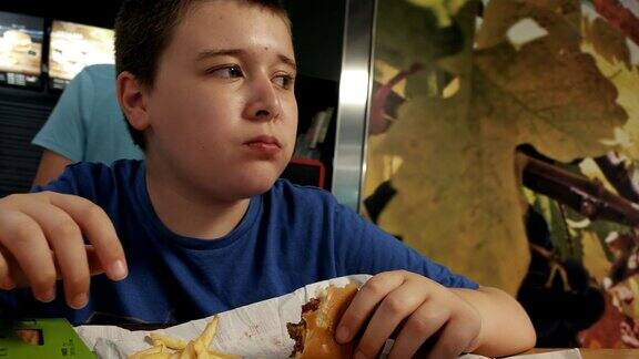 小男孩吃着汉堡包和炸薯条