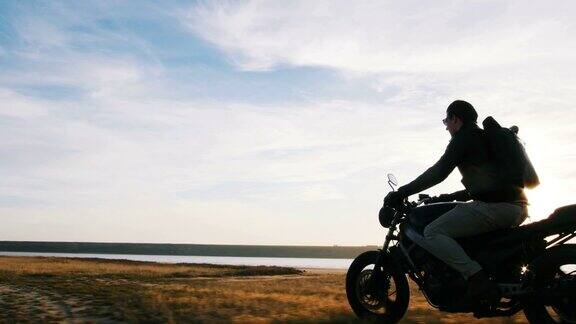 一个骑摩托车的人在日落的路上开着他的摩托车特写镜头