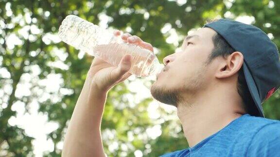亚洲男子饮用新鲜水后在绿色公园