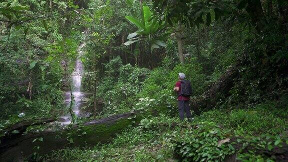 一个人走在瀑布附近的热带森林里