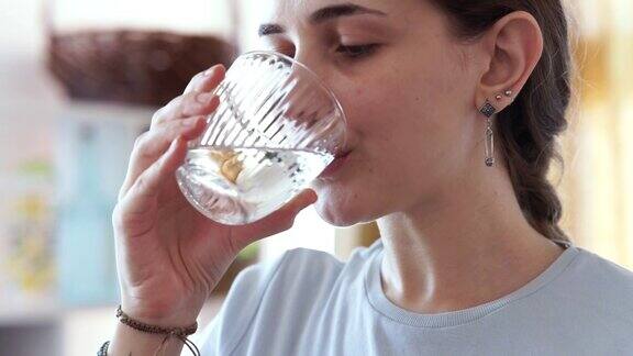 妇女在家里喝着一杯新鲜的水