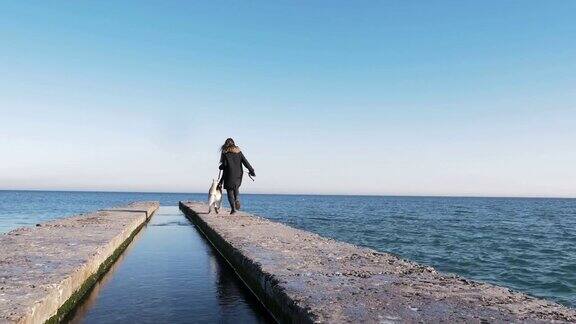 年轻女子和西伯利亚哈士奇在海上码头上奔跑慢镜头