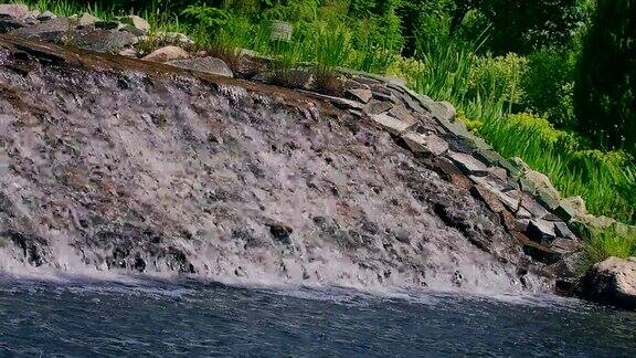 河流在城市公园的石级瀑布上流过清澈的水在岩石上流动