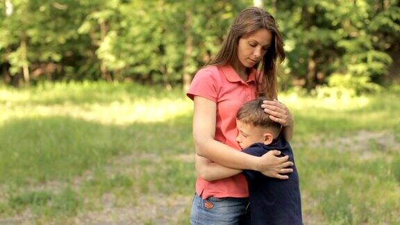 妈妈在公园里轻轻地拥抱她的儿子