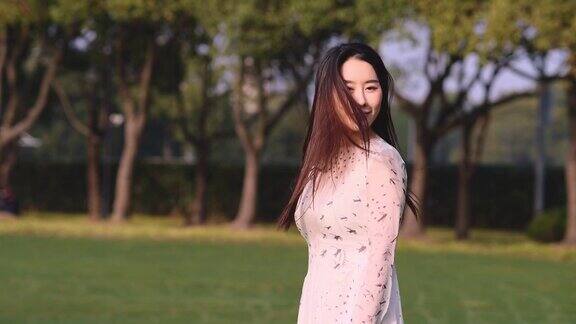 美丽的中国女人与黑色的长发微笑和转身与她的飞扬的头发在风中慢镜头