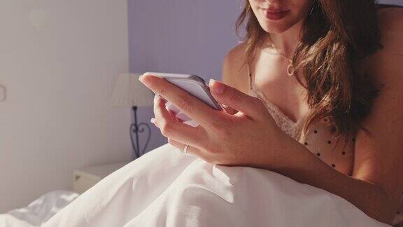 年轻女子清晨躺在床上用智能手机的手特写