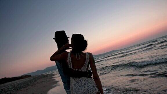 假日里一对年轻浪漫的情侣在日落时分在海滩拥抱