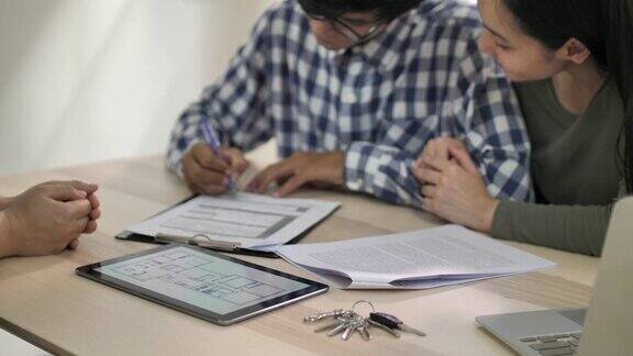 年轻的亚洲夫妇签订合同并购买房子房地产经纪人
