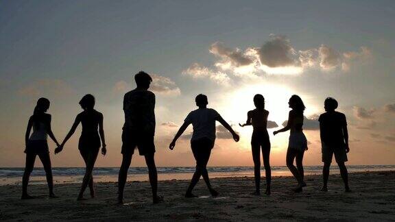 一群微笑的朋友在夏天的海滩上一起跳的剪影友谊海暑假假期和人假期-股票
