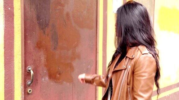 一个拉丁女孩在敲一扇生锈的铁门