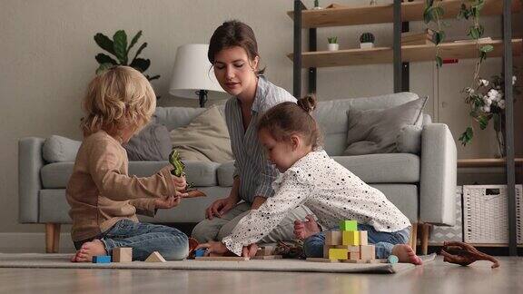 年轻的妈妈和弟妹们在家里玩积木
