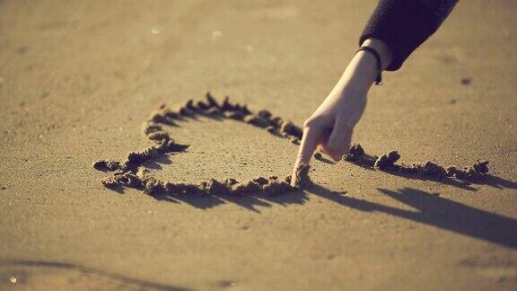 十几岁的女孩在沙滩上画心形