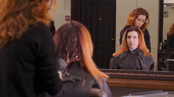 美发师在沙龙里给女孩的长发涂上红色的油漆