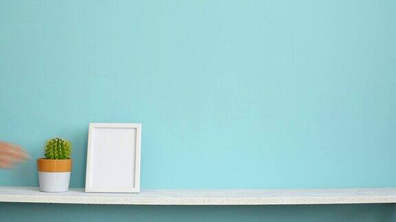 现代房间装饰与画框模型白色的架子对着淡蓝色的墙壁上面放着盆栽的仙人掌